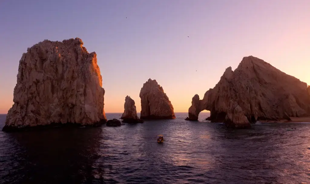 Sunset cruise Cabo San Lucas catamaran sailing past El Arco at golden hour