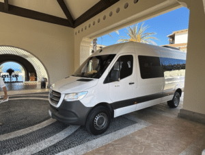 White Mercedes Sprinter shuttle van parked under a resort entrance canopy in Los Cabos