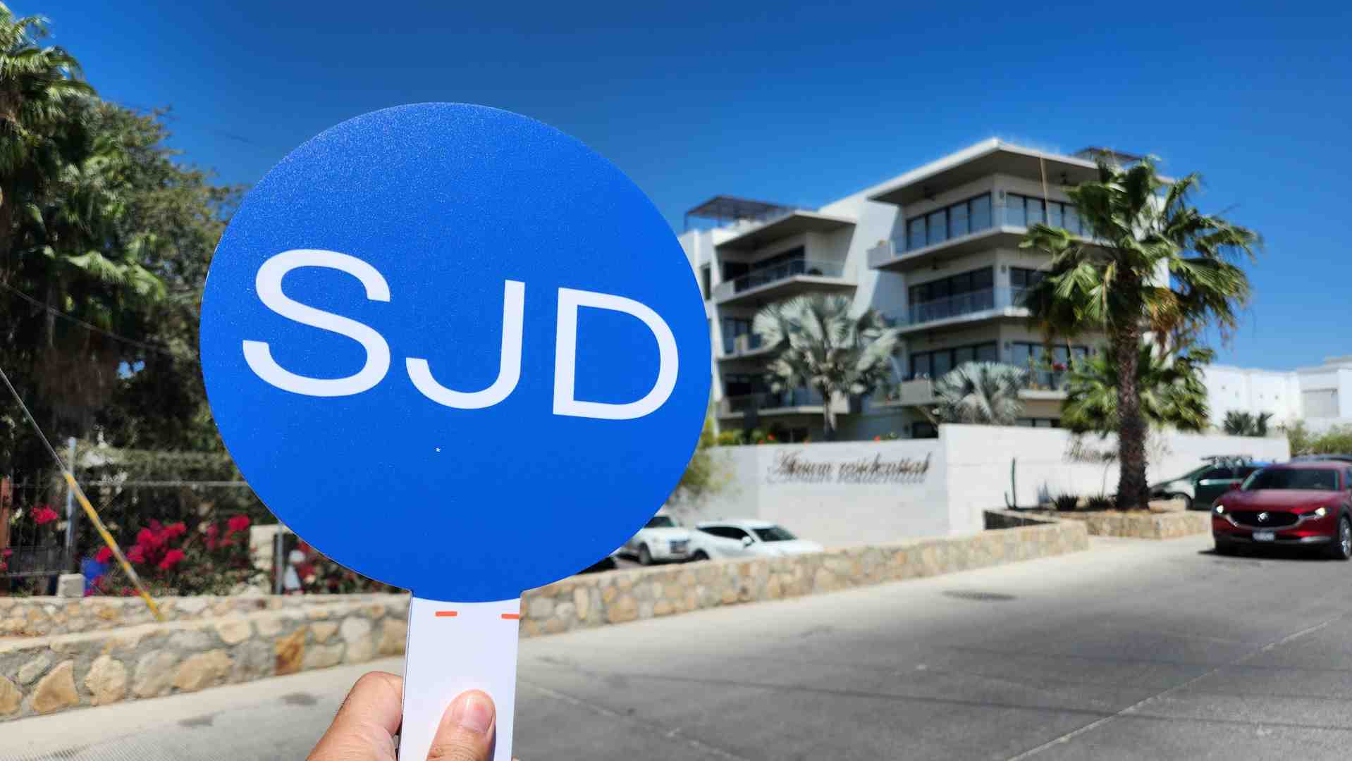 A friendly, uniformed SJD Taxi Airport Shuttle driver holding a sign at the SJD airport arrivals area. - Cabo Activities Transportation